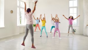 A teacher leads a dance class of young girls with a big leap to represent this blog about the best children's dance franchise businesses for sale in the UK