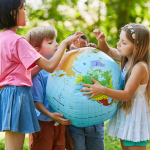 A small group of children gather around to look at a large inflatable globe in an outdoor location to represent this blog about teaching MFL to children with a Spanish language franchise