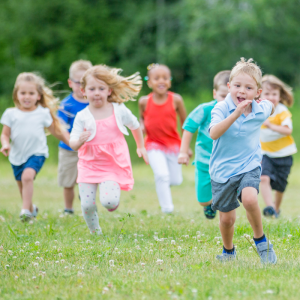 A group of young children run happily across an open field on a warm day to represent this blog about franchise career opportunities for teachers thinking about leaving teaching