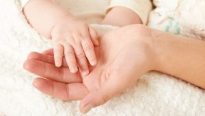 A close up of a mother's hand with her young baby hand's gently holding on to represent this blog about flexible career opportunities after maternity leave