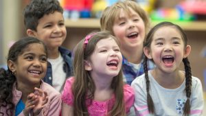 A group of five young children sit together laughing and reacting to represent this blog about the treasure trove of children's franchise opportunities for sale in the UK