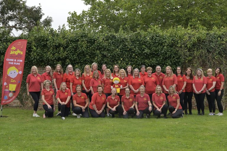 The large team from Jo Jingles music franchise pose together in the outdoors and wearing their red branded t-shirts