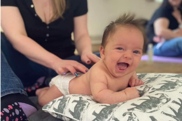 A baby giggles with joy having a massage in a session from The Little Sensory Co. who have sensory franchise opportunities throughout the UK