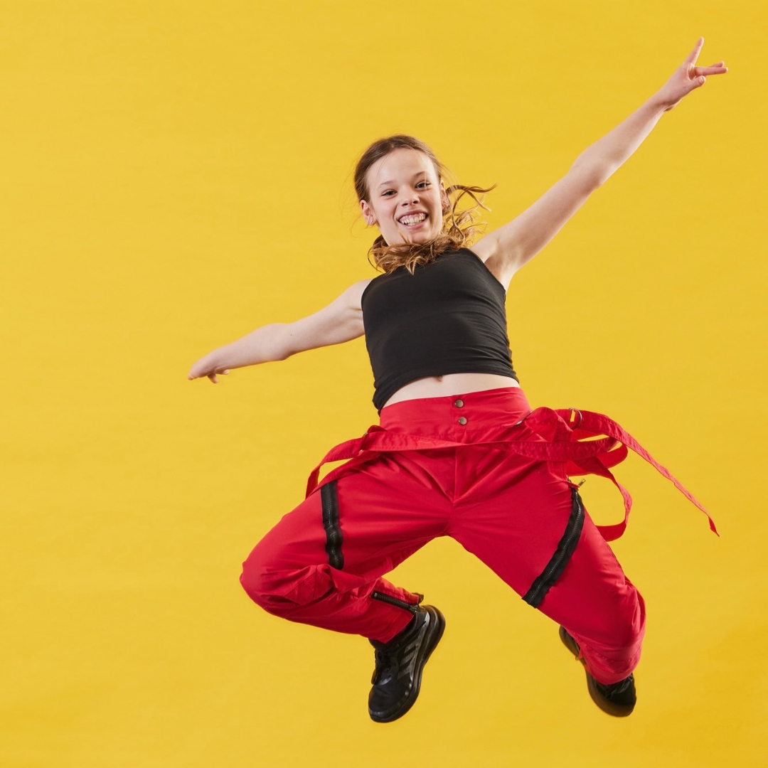 A young female dancer leaps in the air with energy and joy to represent Dance Shack the UK children's performing arts franchise