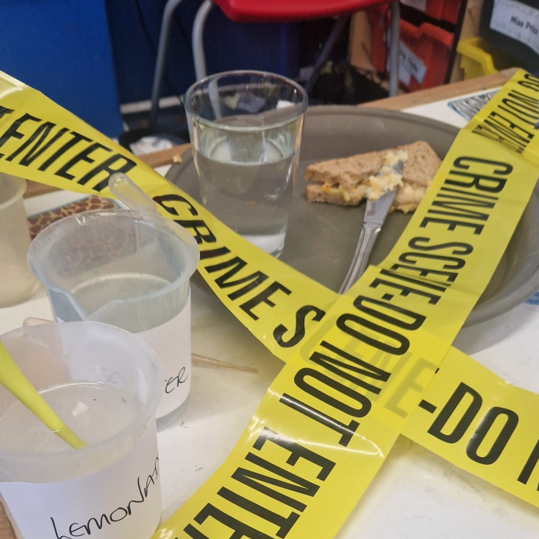 A table with food and drink has been taped and set up as a mock crime scene in this image representing the LoveScience children's STEM franchise opportunity