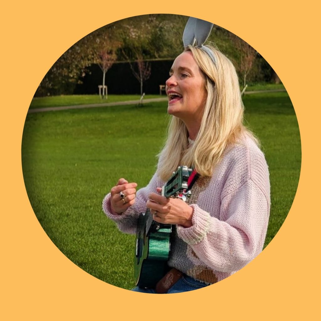 Photograph of Olivia, the franchisor of the Rock Out Baby playing guitar and singing in an outdoor setting while smiling and wearing bunny ears