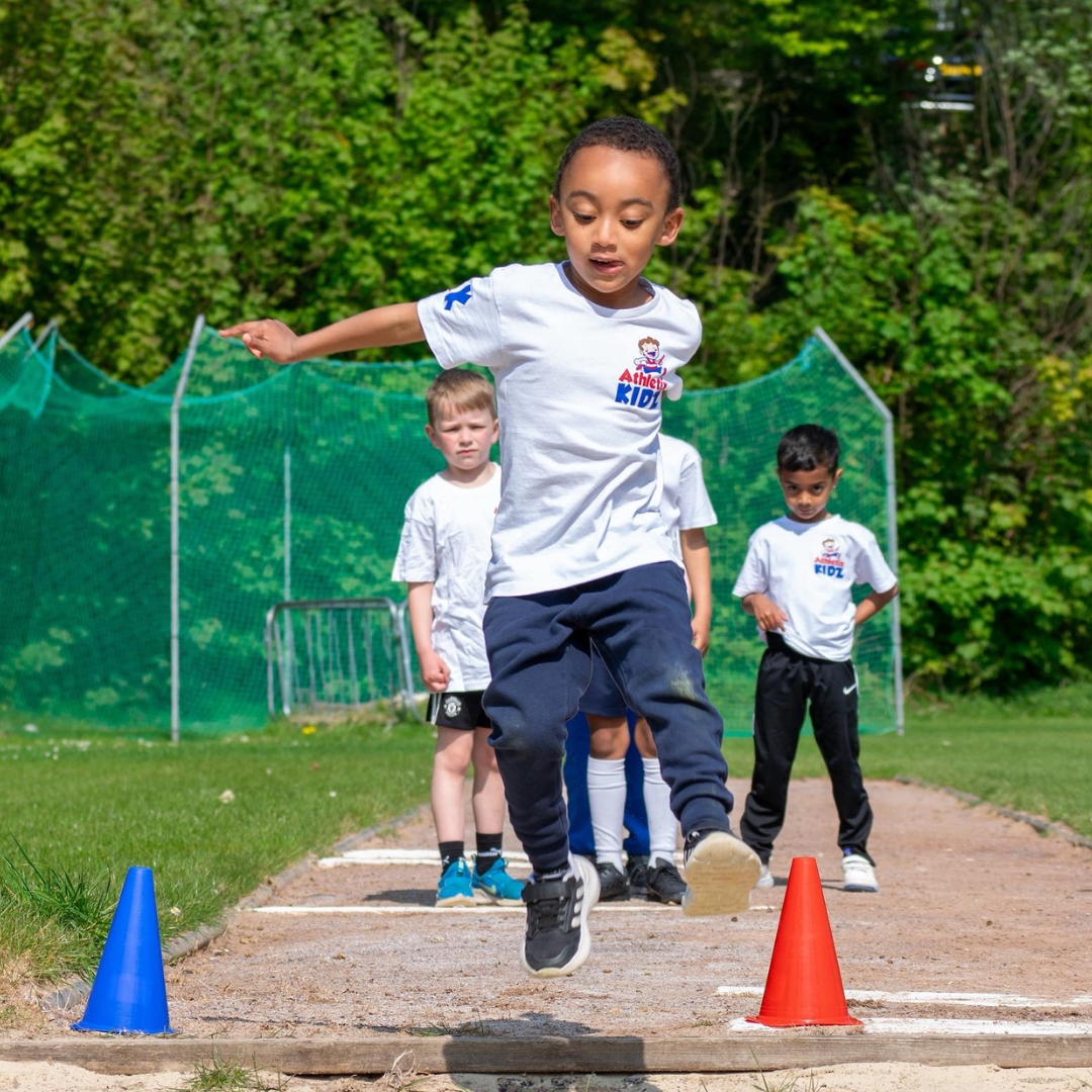 Young children take part in an outdoor long jump activity as part of the Athletix Kidz children's sports franchise opportunity