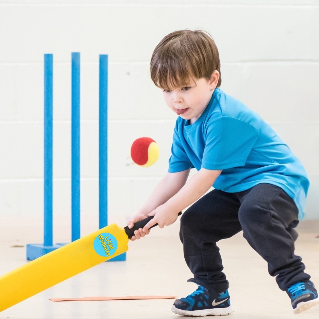 A young boy focusses with his cricket bat extended and poised ready to hit the ball at a fun session with Little Wickets the children's sports franchise