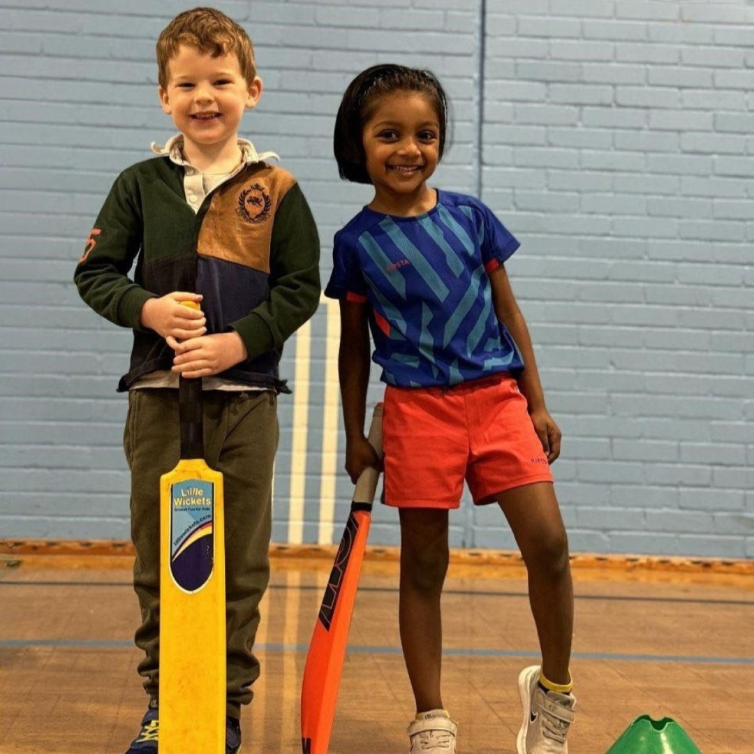 A young boy and girl pose happily with their cricket bats at a fun indoor session with the Little Wickets children's sports franchise brand