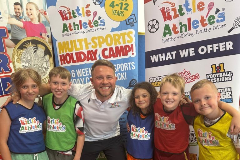 Meet the team from the Little Athletes children's sports franchise brand in this image featuring five smiling children earing colourful branded tabards together with their friendly coach