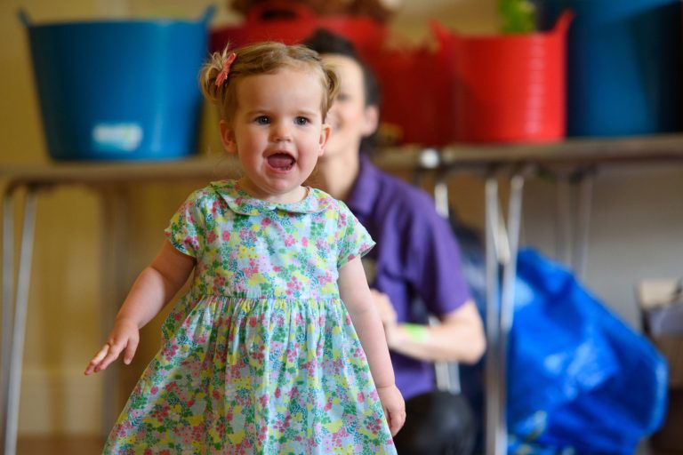 A young toddler girl sings and moves around an inside studio as she enjoys a session from Music Bugs the children's music franchise UK