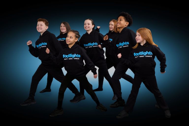 The Footlights children's drama franchise UK is brought to life brilliantly in this professional photo featuring a group of eight young performers in dance mode and wearing branded hoodies.