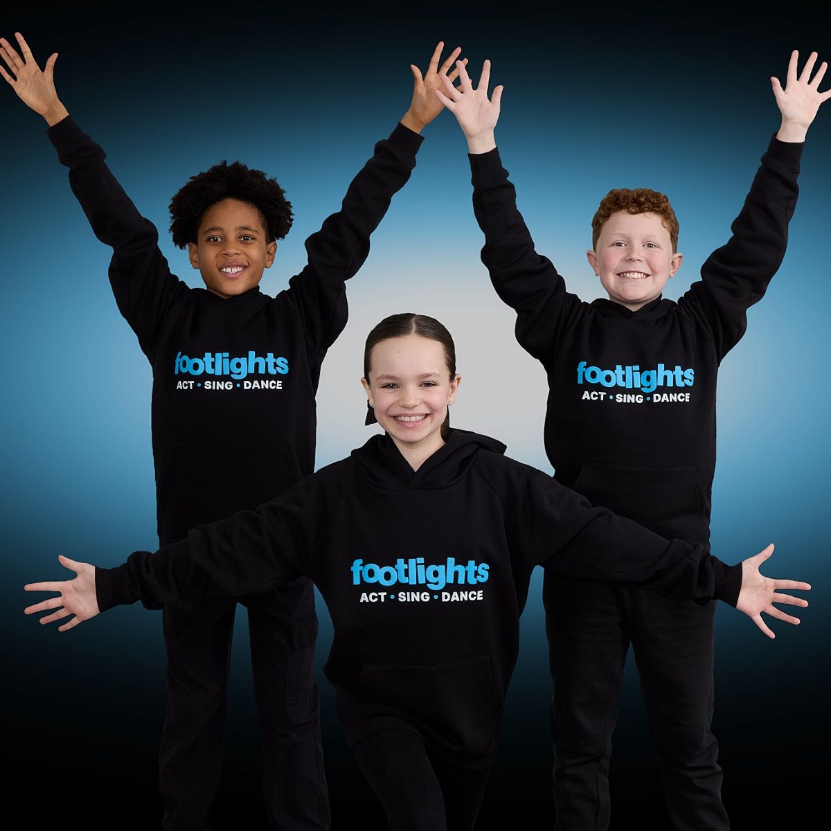 Three young performers pose with their arms out stretched and big smiles on their faces to represent the Footlights drama franchise opportunity for sale